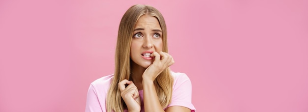 Photo girlfriend broke car feeling cocnerned and scared of man walking towards to argue looking aside with anxiety and panic biting fingernails from stress and troublesome situation posing over pink wall