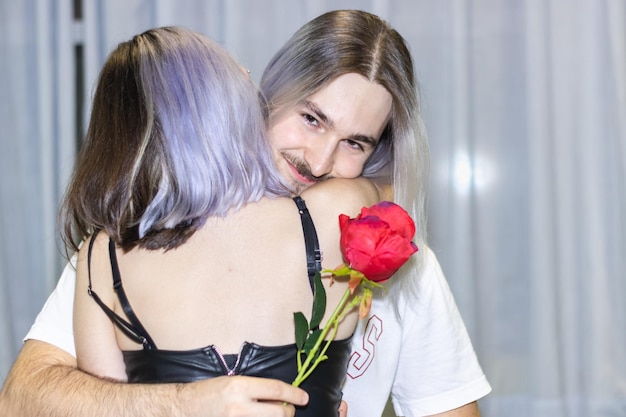 Girlfriend hugging her boyfriend with a rose in her hand Young man hugging girlfriend with a rose in her hand looking at the camera