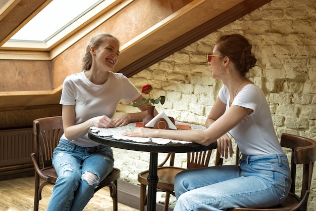 Girlfriend sitting at a table in a cafe, talking and laughing. Friendly conversation, small talk gossip