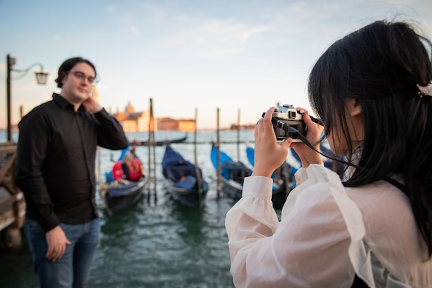 Girlfriend takes a photo of her boyfriend while they are on vacation in Venice tourists visiting the city of love