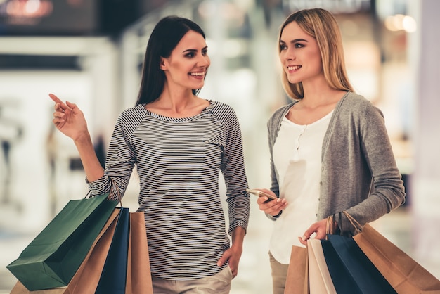 Girls are smiling while doing shopping in the mall