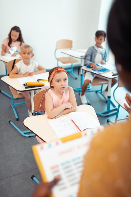 Girls and boy looking and listening to their teacher