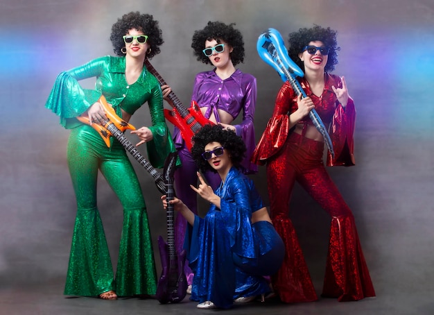 Photo girls in colorful shiny costumes and african wigs with guitars vintage music disco band for women