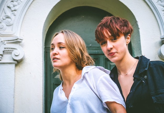 Girls couple standing posing in a dark green door on the street