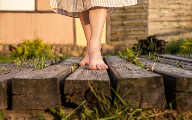 Girls feet walking on wood planks in nature Women barefoot legs going outdoors