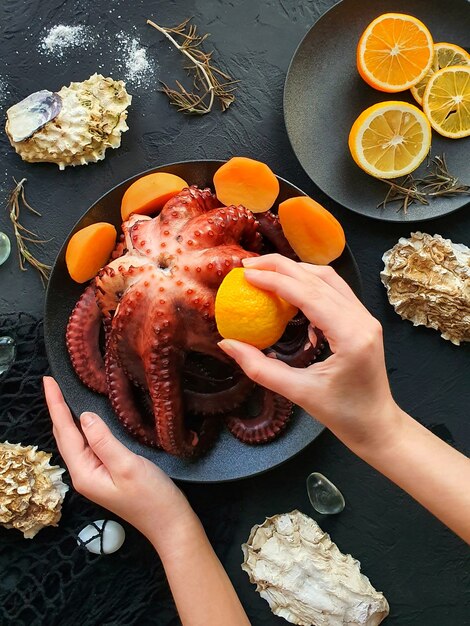 The girls hand pours lemon on a freshly prepared octopus