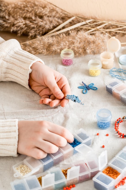 The girls hands are weaving a dolphin on a table with items for beading Development of creative skills and fine motor skills for children Top and vertical view