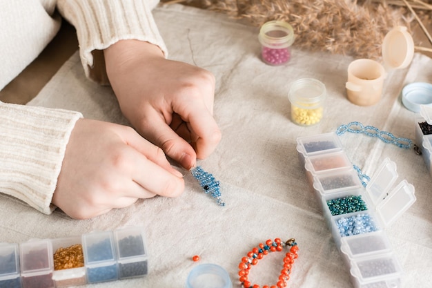 The girls hands are weaving a dolphin on a table with items for beading Development of creative skills and fine motor skills for children Top view