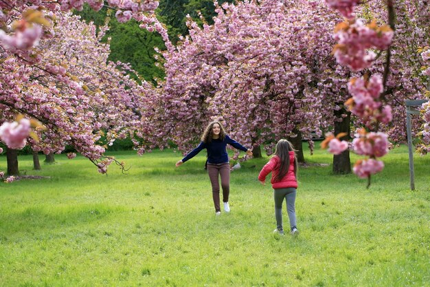 Photo girls have fun in the park of blooming sakura