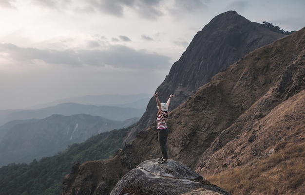 Girls like hiking red and white shirts standing on her back see the beautiful mountains, stretch out her hands naturally fresh. At Mulayit Taung in Myanmar.