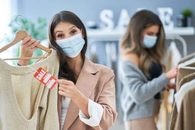 Girls on shopping in store with clothes wearing masks. High quality photo