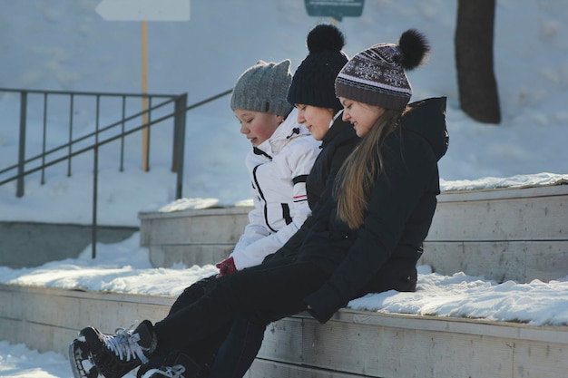 Girls teens wearing skates sit on a bench near the rink and talking