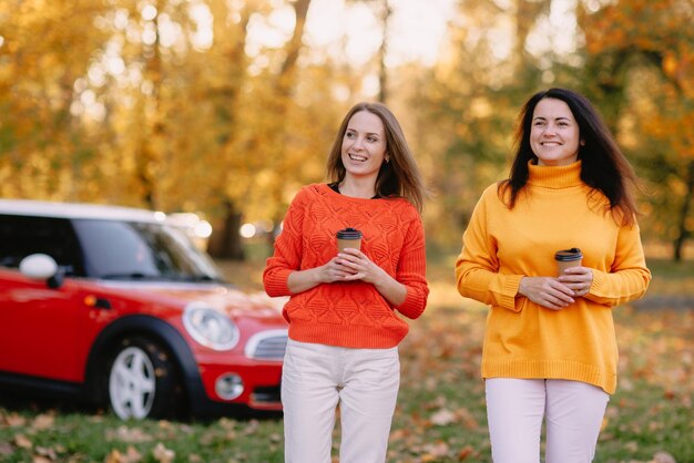 Girls walking in autumn park in red car autumn mood concept