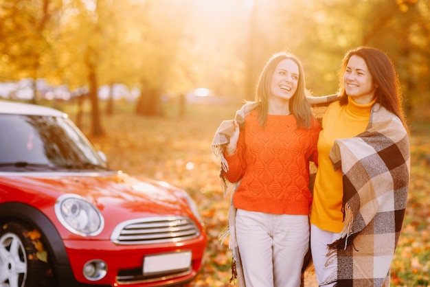 Girls walking in autumn park in red car autumn mood concept