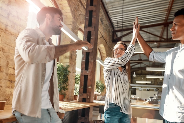 Give me five young man and woman giving highfive while having coffee break with colleagues in the