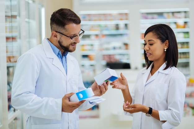 Give me. Handsome bearded pharmacist expressing positivity while working in modern drug store