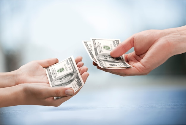 Giving hands with dollars on blurred background