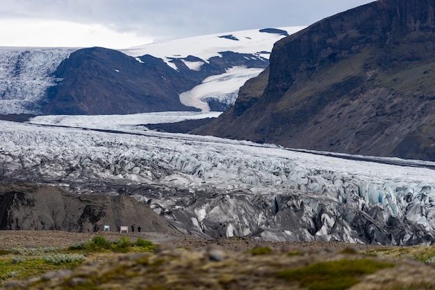 Glacier with ash in the ice with melted water and Icelandic landscape