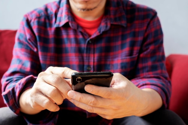 Glad fashionable young bearded guy wears stylish clothes and denim shirt uses free internet connection