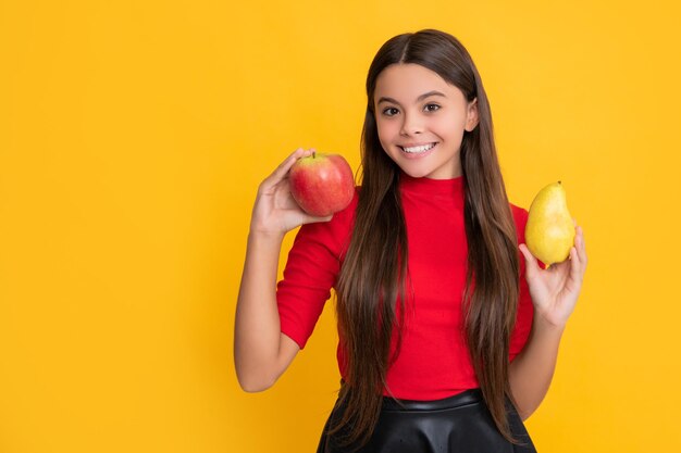 Glad girl hold fresh apple and pear on yellow background