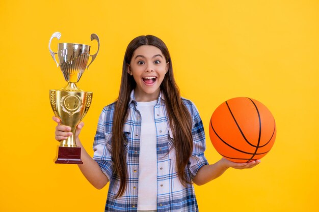 glad teen basketball girl accept award with champion cup isolated on yellow