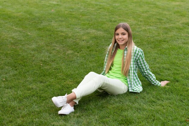 Photo glad teen girl relax on green grass teen girl relax outside photo of teen girl relax