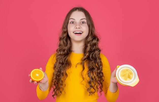 Glad teen kid hold orange and juicer on pink background