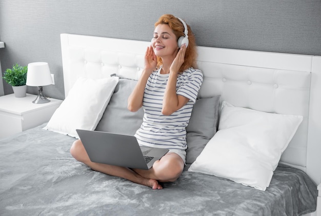 Glad woman listen music in headphones woman listen music at home wearing headphones