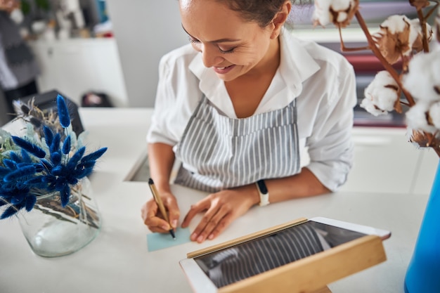 Gladsome lady holding a pen and writing a note