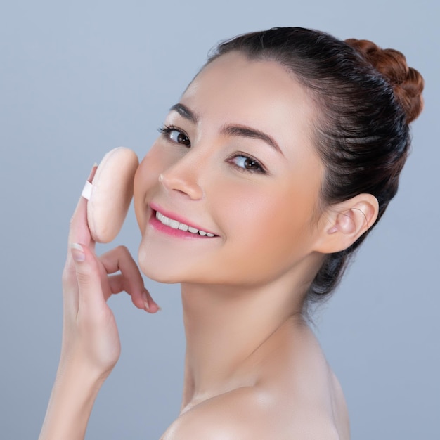 Glamorous beautiful female model applying powder puff for facial makeup concept