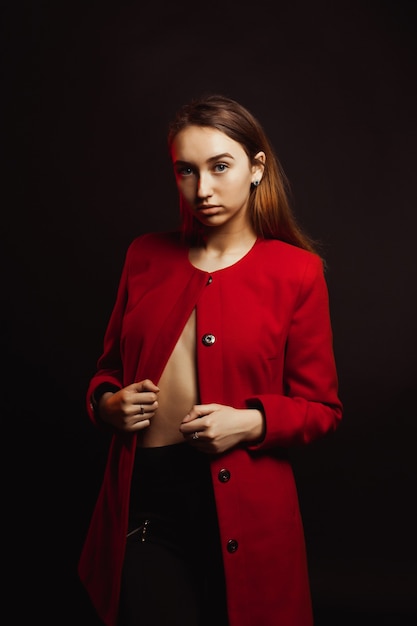 Glamorous brunette woman dressed in fashionable red coat on a naked body