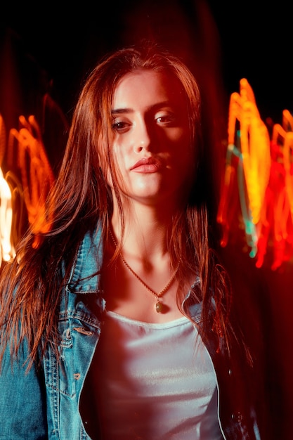 Glamorous brunette woman posing in mixed light technique at the night avenue