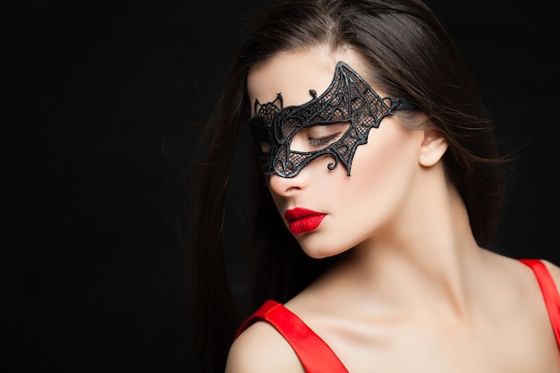 Glamorous fashion model woman in black carnival mask on background with abstract night glitter sparkle