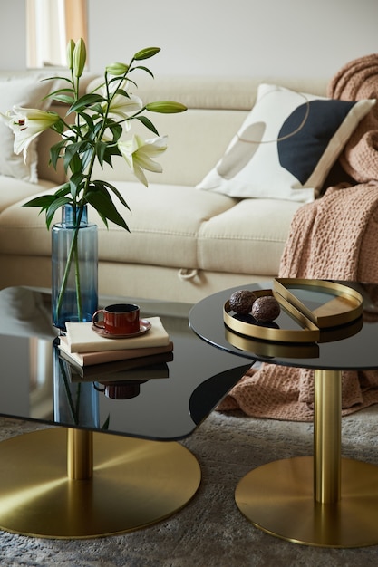 Glamorous living room interior design with modern beige sofa, glass coffee table and golden accessories. Beauty in the details. Template.