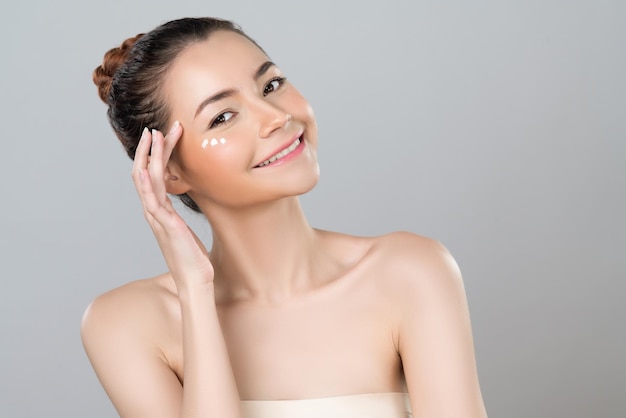 Glamorous woman applying moisturizer cream on her face for perfect skin