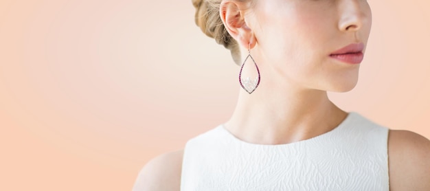 glamour, beauty, jewelry and luxury concept - close up of beautiful woman face with pearl earring over beige background