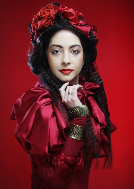 Glamour fashion model in elegance red costume with red hat. Studio shot.