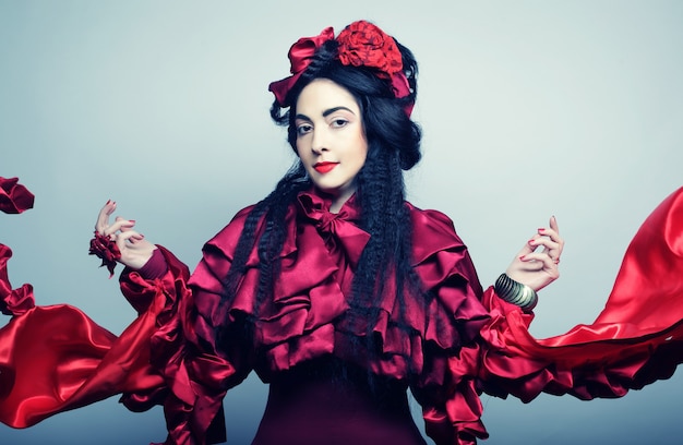 Glamour fashion model in elegance red costume with red hat. Studio shot.