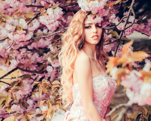 Glamour girl in pink blossom Beauty girl on blooming sakura blossoms flowers on nature surface