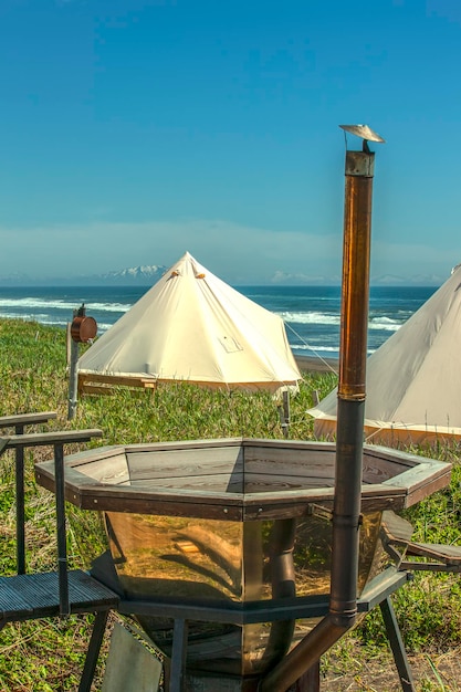 Glamping house and outdoor bath tub on ocean coast rural landscape tent houses in Kamchatka peninsula Selective focus