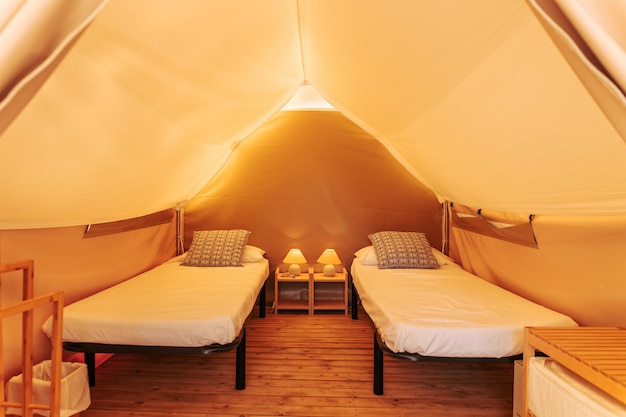 Glamping tent cozy interior with beds on a sunny day Glamorous camping tent for summer lifestyle