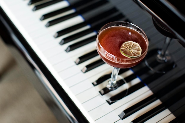 A glass of alcoholic cocktail on the background of a piano.