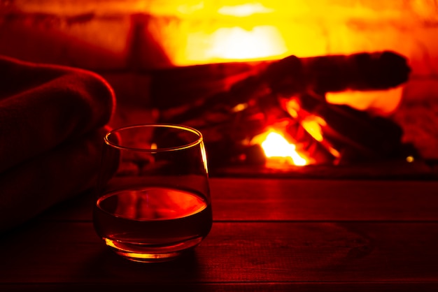 Glass of alcoholic drink wine in front of warm fireplace. Magical relaxed cozy atmosphere near fire