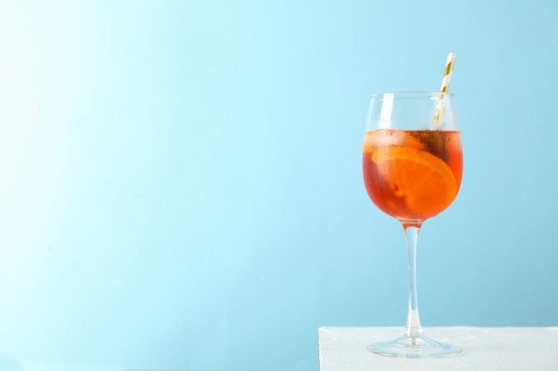 Glass of aperol spritz cocktail against blue