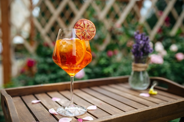 Glass of aperole spritz cocktail garnished with orange slice on the wodoen tray