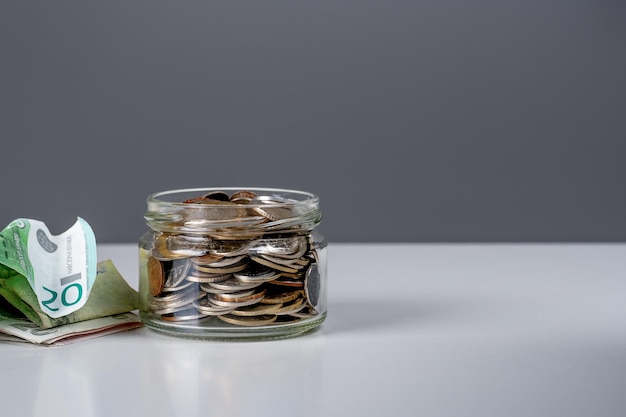 Glass bank for tips with money charity donation Tip jar with money Coin in a jar on dark gray background Business financial and saving money concept