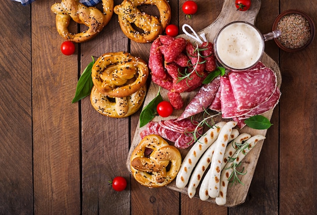 Glass of beer, pretzels and various sausages on wooden background. Oktoberfest.