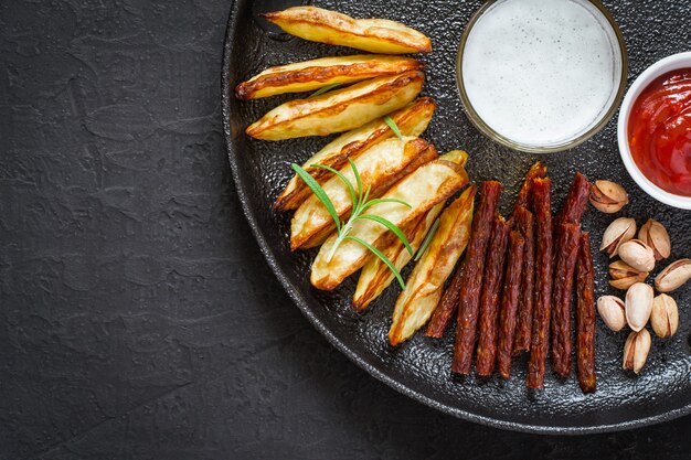 Glass of beer and a selection of snacks on cast iron dish.