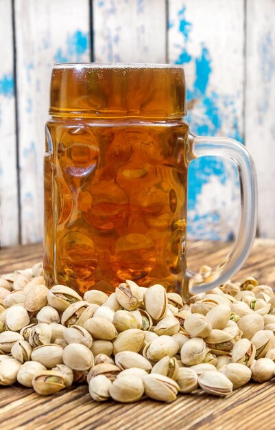 A glass of beer with pistachios on a wooden table