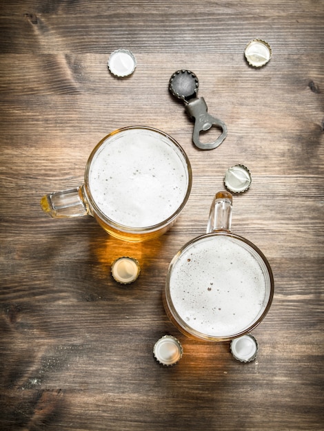 Glass of beer with stoppers and a bottle opener. on a wooden table.